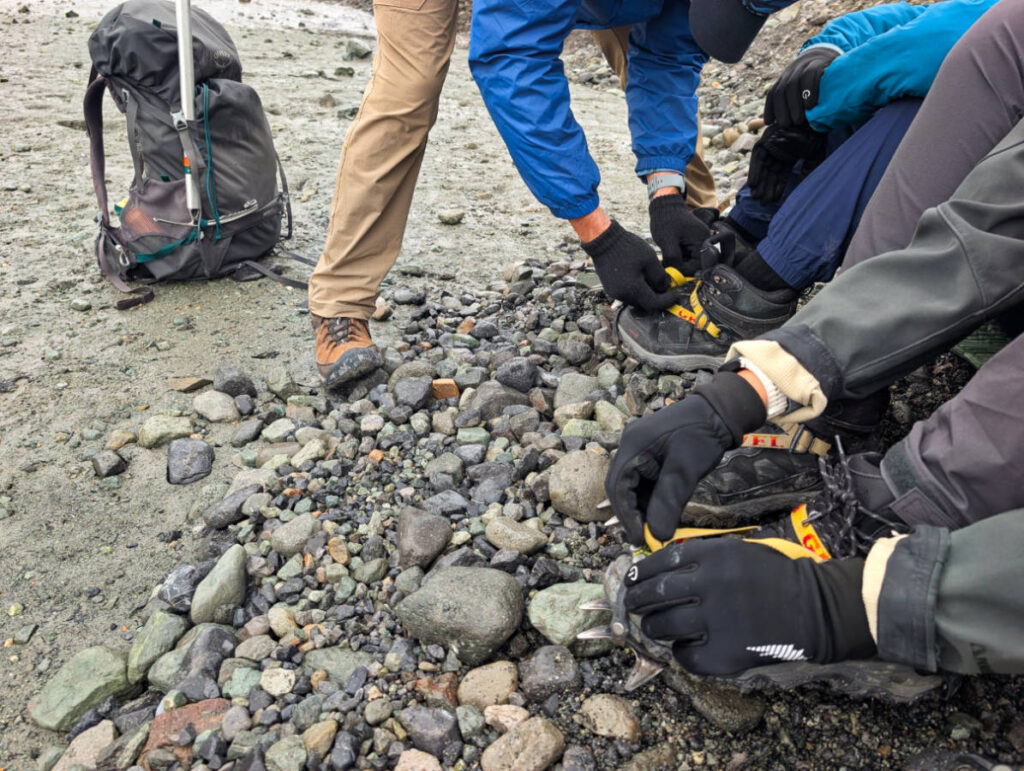Taylor Family putting on crampons on Root Glacier with Kennicott Wilderness Guides in Wrangell St Elias National Park McCarthy Alaska
